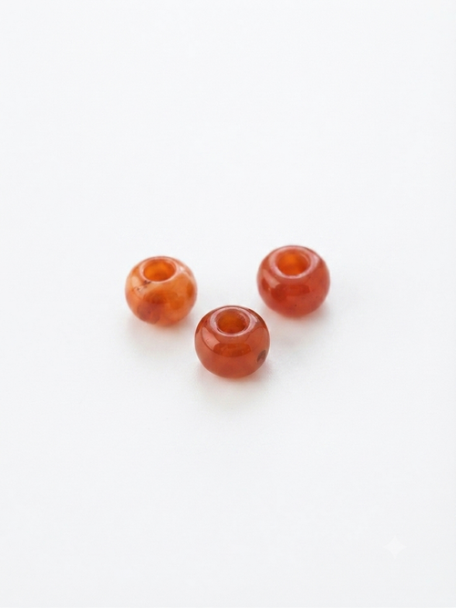 Orange-red carnelian round crystal beads on a white background