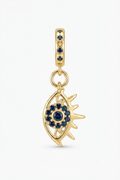 Gold-tone sun eye charm with blue crystals on a white background