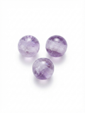 Purple translucent round crystal beads on a white background