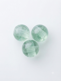 Clear green round crystal beads on a white background