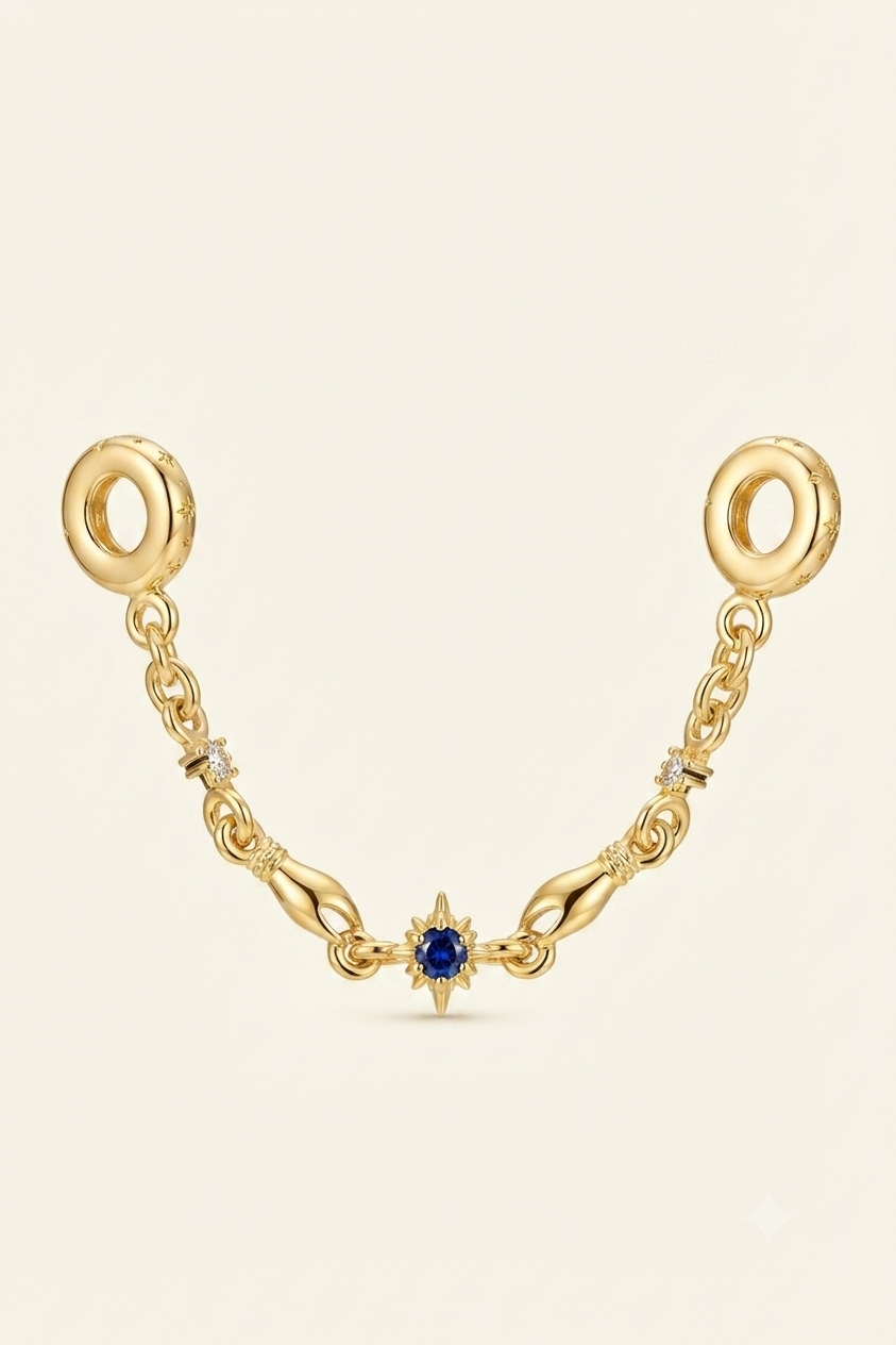 Gold-tone safety chain charm with a blue star crystal on a white background