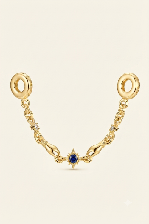 Gold-tone safety chain charm with a blue star crystal on a white background